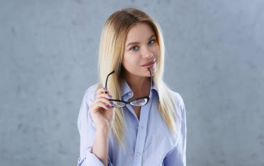 Seksi bir kadın portresi bir mans gömlek gri bir arka plan üzerinde gözlük kameraya bakar ve gülümseyerek bakmak tavsiye vermek istiyor itirazları kabul edilmez.