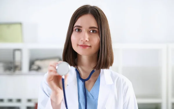 Female medicine doctor hand holding stethoscope head closeup in front of her chest. Medic shop or store physical and disease prevention er consultant 911 pulse measure healthy lifestyle concept