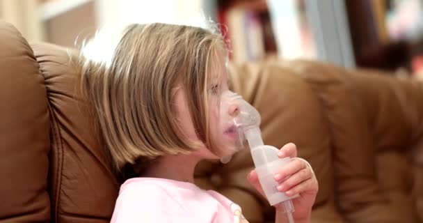 少女はソファに座ってマスクで自宅で吸入を行います 気管支炎の咳や子供の炎症の治療 — ストック動画