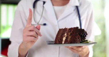 Doktor eli çikolatalı pasta tutuyor ve dikkat çekmeye çalışıyor. Şeker ve diyetin faydaları ve zararları