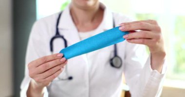 Eldivendeki doktor elinde kineziyoloji bandı tutuyor. Kineziyoloji bandı ve spor sakatlıkları