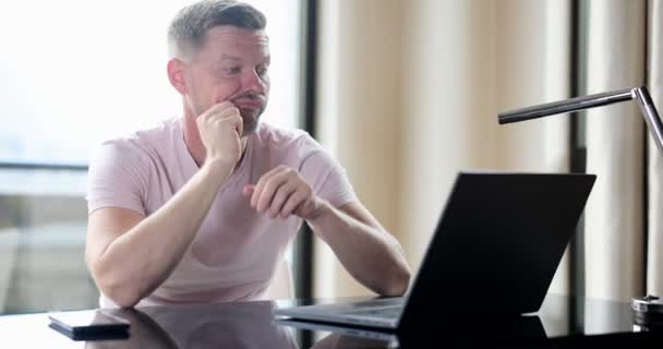 Verveelde Man Controleert Online Laptop Inhoud Zittend Tafel Thuis Zenuwachtige — Stockvideo