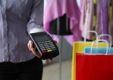 Mağazadaki kadın müşteri hizmetleri terminalini tutuyor. Kurulum ve terimler ticaret POS terminalini kullanır. Mobil cihazla alışveriş için ödeme yap. Ürün ve hizmetler için temassız ödemeyle güvenli bir şekilde ödeme yapın