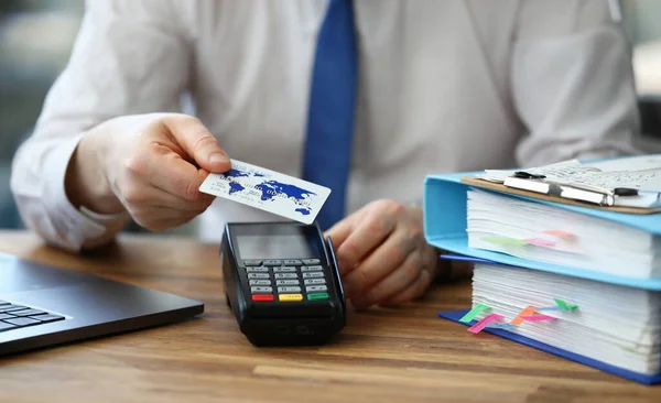 Office employee shows credit card and terminal. Banking application. POS-terminal communications are provided by bank. Electronic services bank. Payment for services through online banking