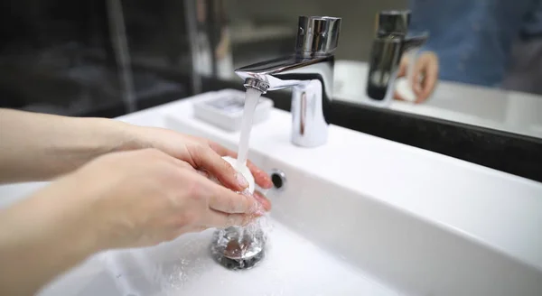 Man thoroughly washes his hands with soap under tap. Disposable hand disinfection during pandemic. Psychological phobia, fear germs. Infection prevention. Clean hands protect against illness