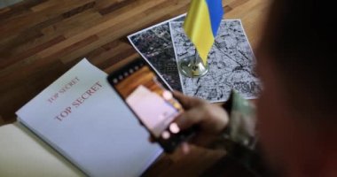 Ordu casusu Ukrayna karşı taarruzu hakkındaki belgeleri inceliyor ve akıllı telefonuyla fotoğraf çekiyor. Ukrayna ve Rusya Savaşı