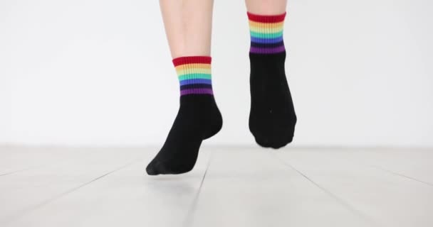 装飾されたLgbtの旗を持つ靴下の人が床にジャンプしています 性的マイノリティーを支援するデモ — ストック動画