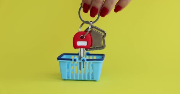 黄色の背景に家の鍵を持つミニチュアバスケット 不動産住宅ローンや社会住宅の購入 — ストック動画