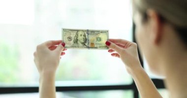 Elinde 100 dolar olan sahte parayı kontrol ediyorum. Yeni yüz dolarlık banknottaki filigranı kontrol et.