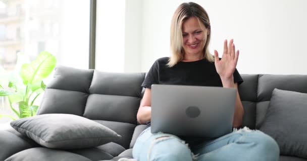Χαμογελώντας Νεαρή Γυναίκα Που Χρησιμοποιεί Φορητό Υπολογιστή Κάθεται Στον Καναπέ — Αρχείο Βίντεο
