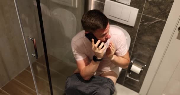 Homme Nerveux Assis Sur Les Toilettes Parlant Tranquillement Sur Smartphone — Video