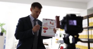 İş ortaklarının çevrimiçi toplantısı, iş adamlarının grafiğini kameraya gösteriyor. İyi mali sonuçlara sahip blog analisti ofiste belge finansörüyle çalışıyor