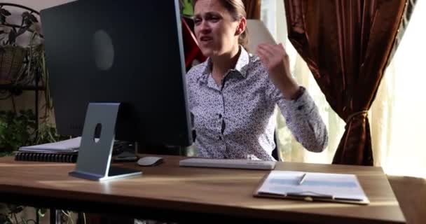 コンピュータの隣のテーブルに座っている激怒した女性は壊れたモニターを身に着けている マルウェアと誤動作とコンピュータ修復の概念 — ストック動画