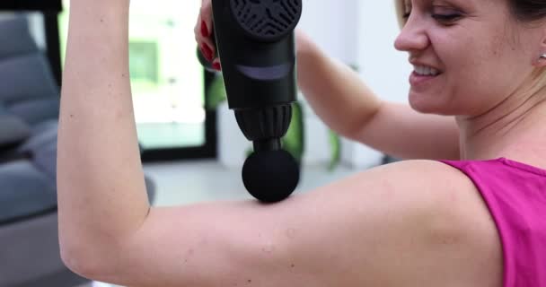 アスレティックウーマンは腕の筋肉痛にマッサージを使用します 体のリラクゼーションのためのマッサージ銃 — ストック動画