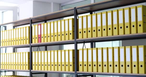红色的文件夹在架子上移动 在档案库中一排相同的黄色文件夹 业务文件的储存 — 图库视频影像