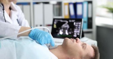 Hastanedeki ultrason cihazında hasta için tiroid taraması. Doktor ultrason çeviriciyi hastanın boynuna geçirip ekrana bakıyor.