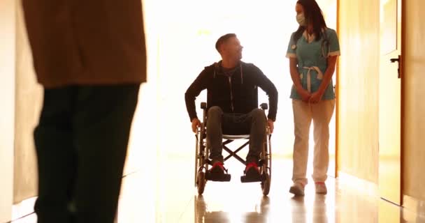 Nurse Walks Hospital Corridor Talks Patient Wheelchair Medical Assistance Disabled — Stock Video