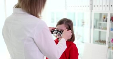 Görme kliniğinde gözü gören bir çocuk. Oftalmolog görme tedavisi için gözlük seçmeye yardımcı olur