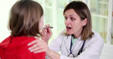 Klinikte çocuğun boğazının doktor tarafından incelenmesi. Çocuklarda ve viral bademcik iltihabı.