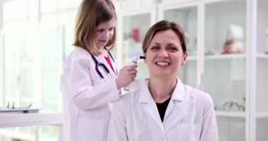 Çocuk doktoru kız steteskopla kadın doktor ENT 'ye bakıyor. Arkadaş canlısı doktor çocuk teması ve tıp eğitimi