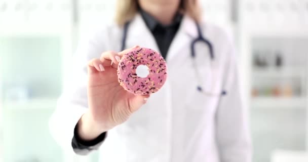 栄養士は手を閉じてピンクのドーナツを保持しています 健康のためのお菓子の危険 — ストック動画