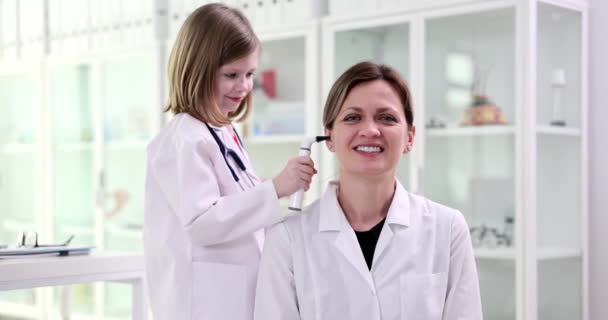 小女孩在诊所用耳镜看医生的耳朵 儿科医生与儿童玩耍 并检查儿童和成年人的听力 — 图库视频影像