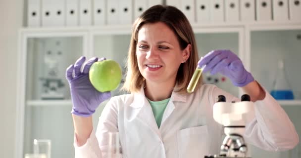 科学家生物学家手里拿着一个新鲜的苹果和一个装有绿色液体样品的管子 Gmo水果研究和毒素 — 图库视频影像