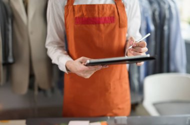 Önlüklü kadın yönetici not alıyor, yakın plan. Çamaşır ve kuru temizleme servisi, ev işi.