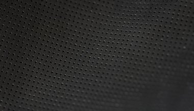 Siyah deri kumaş desenli küçük delikler, yakın plan. Delinmiş mat dokusu. Koyu arkaplanın makro görüntüsü