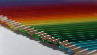 Renkli kalemler masanın üstünde duruyor, yakın plan, bulanık. Renk paleti yeşilden kırmızıya. Eğitim