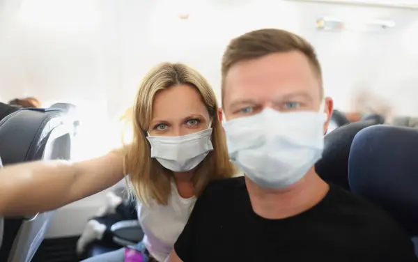 Family couple in protective masks on the plane, close-up. Protective measures against coronovirus during flight, vacation