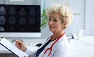 Gülümseyen yaşlı bir doktorun klinikteki hasta hastaya teşhis koymasına yakın çekim. Neşeli kadın kameraya sevinçle bakıyor. Sağlık ve Tıp Konsepti