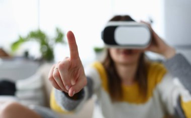 VR deneyimi sırasında güzel bir kadının havaya dokunuşunun yakın çekimi. Sanal gerçeklik gözlüğü takan genç bir kadın. Eğlence ve modern teknoloji konsepti