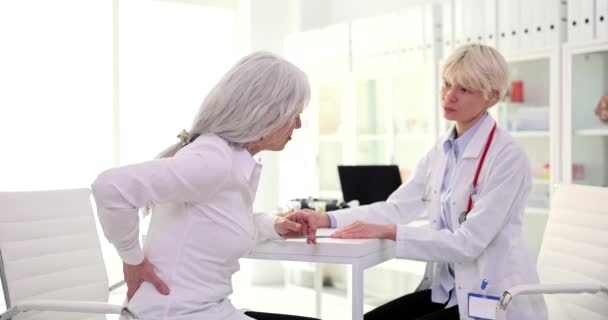 老年妇女病人抱怨肾部疼痛 医生在诊所4K片慢动作治疗 老年患者骨质疏松症诊断与治疗的概念 — 图库视频影像