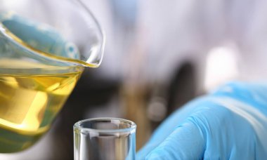 Motor yağı otomatik vites ve hidrolik yükseltici kimya test tüp elinde üretir koruyucu eldiven erkek el ele tutuşur