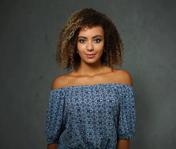 Güzel siyah kadın portre. Bir gri arka plan ve gülümseyen güzellik moda stil kıvırcık saçlı beyaz lifler görünüm göz kamera ile değer