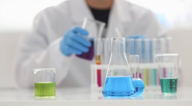 Bir erkek kimyager tüp elinde cam taşmaları potasyum permanganat yürüten bir analiz tepki alır çeşitli sıvı bir çözüm tutan kimyasal üretim kullanarak reaktifler sürümleri.