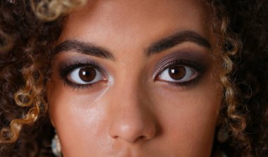 Güzel siyah kadın portre. Bir gri arka plan ve gülümseyen güzellik moda stil kıvırcık saçlı beyaz lifler görünüm göz kamera ile değer