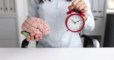 Kadın, insan beyni ve alarmlı saatin bir maketini ileri doğru geriyor. Zeka ve zeka geliştirme kavramı