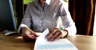 İş kadını ofisteki masada grafiklerle sayfa sayfa açıp 4K 'lık filmi yavaş çekimde çekiyor. Ticari başarı stratejisi kavramı