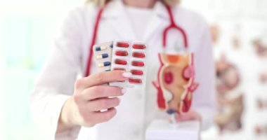 Doktor proktolojist elinde haplarla kabarcıklar tutuyor ve anatomik model rektum kapanış filmi ağır çekim. Basur ve rektal çatlakların tedavisi kavramı