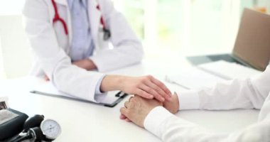 Doktor hastaya elini uzatıyor ve yakın çekim 4K filmi ağır çekimde sempati duyuyor. Tedavisi olmayan hastalara psikolojik yardım