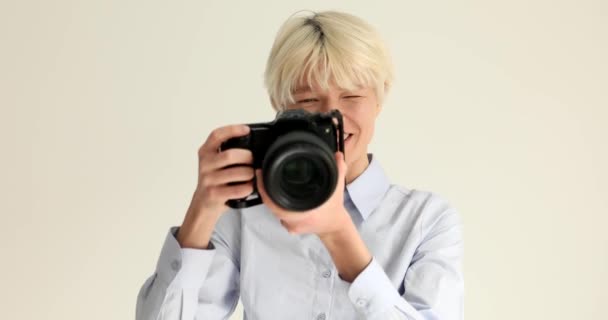 Женщина журналист делает фотографии с черной профессиональной камерой на белом фоне 4k фильма замедленной съемки. Концепция фотографии хобби