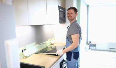 Mutfağa yemek sobası koyan neşeli tamircinin portresi. Taşınmaya yardım eden üniformalı profesyonel bir servis çalışanı. Yeni mülk. Yenileme ve iç tasarım konsepti