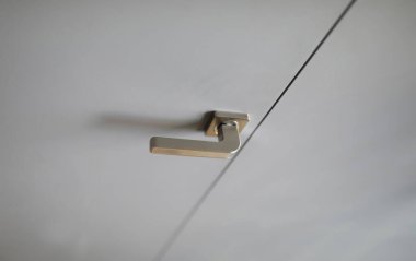 Beyaz kapıya paslanmaz çelik kapı tokmağı yakın plan. Kesişen kapının makro görüntüsü. Ev eşyalarının ayrıntıları. Ev içi ve yenileme konsepti