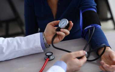 Hasta hastaya tonometre tutan ve basıncı ölçen doktor ellerinin yakın çekimi. Klinikteki yaşlı kadını muayene eden terapist. Sağlık ve Tıp Konsepti
