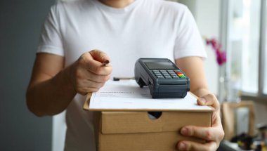 Karton kutu ve ödeme terminalini elinde tutan adamın yakın çekim görüntüsü. Kredi kartıyla ulaşılamıyor. Paket teslimatı ve modern teknoloji konsepti