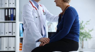 Close-up of unhealthy woman on appointment with therapist. Doctor in uniform making examination of sick elderly lady. Health care, treatment and medicine concept clipart