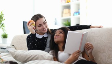 Çekici mutlu arkadaşların ilginç bir şeyi tartışıp kitap okuyan portresi. Evdeki rahat atmosfer. Kızlar kanepede oturup dedikodu yaparak eğleniyorlar.