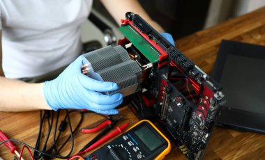 Bilgisayarla çalışan koruyucu eldivenli kişilere yakın çekim. Tahta masada duran voltajı ölçmek için voltmetre. Diy ve hobi konsepti